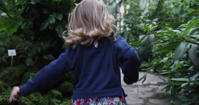A little girl in a jungle dress runs away from the camera