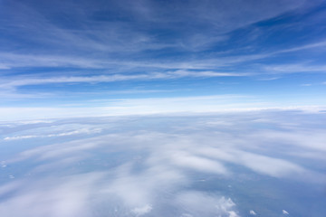 Fototapeta na wymiar Skyscape view from clear glass window seat from aircraft to cloudscape, traveling on white fluffy clouds and vivid blue sky in a suny day