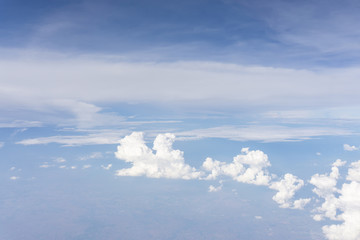 Skyscape view from clear glass window seat from aircraft to cloudscape, traveling on white fluffy clouds and vivid blue sky in a suny day