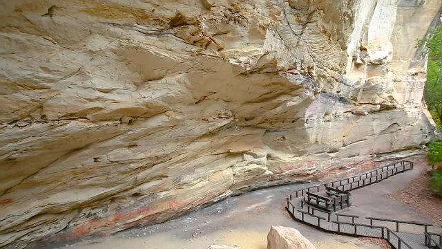 Left to right pan motion of cliff face know as Cathedral Cave at end of walking trail of Carnarvon Gorge. Walls have engravings, Ochre stencils, free-hand paintings which most are 1000's of years old 