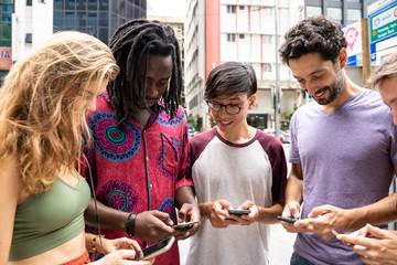 Multiracial group together on the street with mobiles in hand