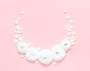 Circle frame made of ranunculus flowers on a light pink background