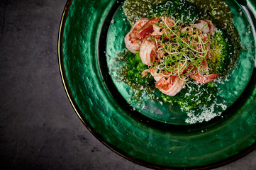 boiled shrimps on a green plate with microgreen on a gray background