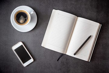 Business flatlay. Minimalism. Notepad, pen, phone and a cup of coffee. Time for reflection. Entries in the diary. Top view