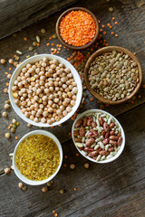 Diet and healthy eating concept, vegan protein source. Raw of legumes (chickpeas, red lentils, canadian lentils, beans, bulgur) on wooden table. Top view on a flat lay.