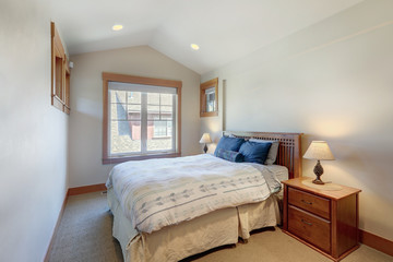 Guest bedroom with wooden bed and great windows with beige carpet. white and blue sheets.
