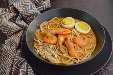 Laksa noodle soup with prawn, egg and bean sprouts. Garnish with lime and mint leaf
