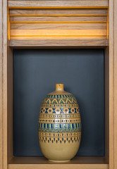 Beautiful yellow ceramic terracotta vase geometric pattern on wooden cabinet interior modern office...