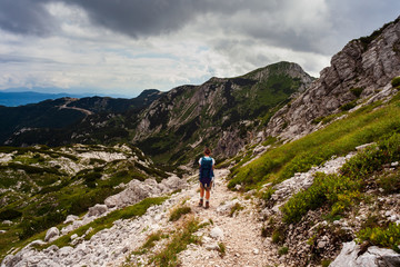 Fototapeta na wymiar Young woman with backpack hiking along the path in the Vogel mountain, Slovenia
