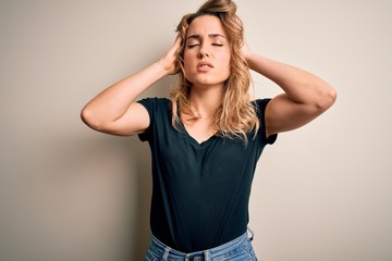 Young beautiful blonde woman wearing casual t-shirt standing over isolated white background suffering from headache desperate and stressed because pain and migraine. Hands on head.