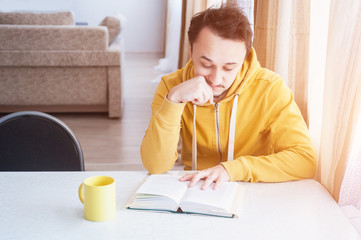 A man is sitting at a table reading a book