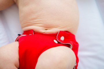 Mother changing reusable diaper or nappy. Reusable diaper and infant. Baby with eco diaper. 