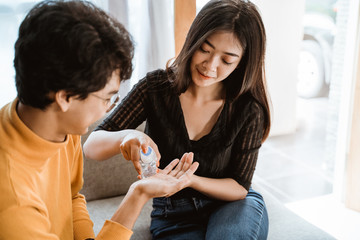 asian woman and man using hand sanitizer at home