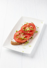Sandwich with soft cheese and tomatoes. Bright wooden background.