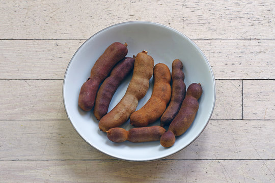 A bowl of fresh tamarind fruit pods
