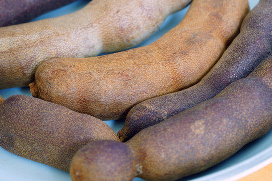 A bowl of fresh tamarind fruit pods
