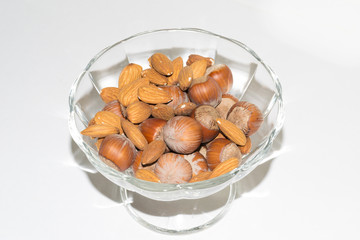 Close up view of shelled hazelnuts and almonds isolated on a white background. A bunch of hazelnuts in a rosette as a background. Macro view of peeled almonds peeled from hazelnuts.