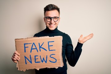 Young handsome caucasian man holding protest carboard for desinformation and fake news very happy...