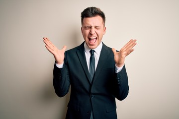 Young handsome business man wearing elegant suit and tie over isolated background celebrating mad and crazy for success with arms raised and closed eyes screaming excited. Winner concept