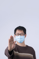 Portrait of young Asian man, saying no to coronavirus infection with wearing medical surgical blue face mask isolated on white background, close up, closeup.