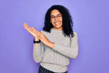 Young african american woman wearing casual sweater and glasses over purple background clapping and applauding happy and joyful, smiling proud hands together