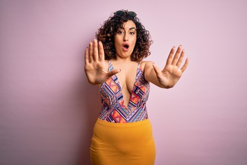 Young beautiful arab woman on vacation wearing swimsuit and sunglasses over pink background doing...