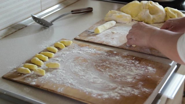 cook Halusky potatoes,woman in the kitchen cooks dumplings of dough and potatoes, twists the dough and cuts into pieces