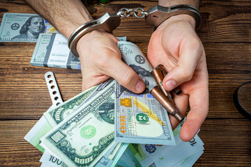 hands with handcuffs, knife and ammunition with money banknotes.