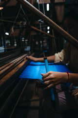 Woman's hands working Cambodian silk on a loom