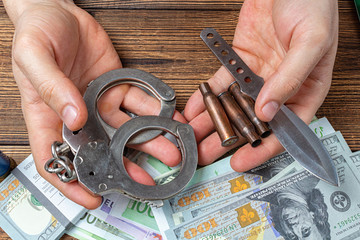 hands with handcuffs, knife and ammunition with money banknotes.