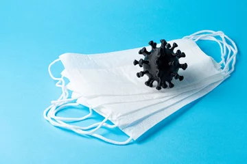 Fototapeten Pandemic COVID-19. White medical masks and coronavirus on a blue background, copy space. © EduardSkorov