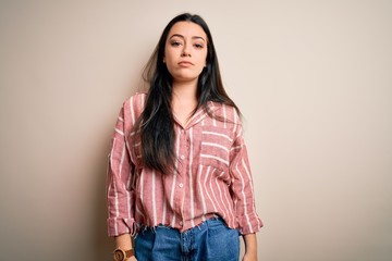Young brunette woman wearing casual striped shirt over isolated background Relaxed with serious expression on face. Simple and natural looking at the camera.