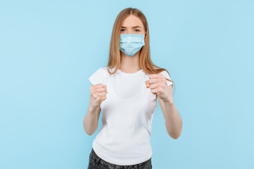woman in a protective medical mask on her face shows a gesture of struggle and protection. Air...