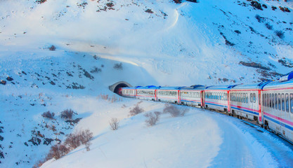 Red diesel train (East express) in motion at the snow covered railway platform - The train connecting Ankara to Kars - Passenger train going through tunnel 