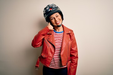 Fototapeta premium Middle age motorcyclist woman wearing motorcycle helmet and jacket over white background smiling doing phone gesture with hand and fingers like talking on the telephone. Communicating concepts.
