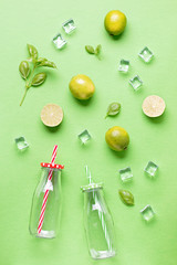 Flat lay with ingredients for summer refreshing drink or smoothie, ice cubes, herbs and glass jars on green background, top view. Strawberry, lime, ice and basil for delicious summer cocktail