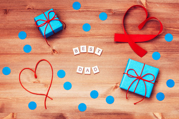 Happy fathers day best dad words made of wooden blocks with blue gift boxes and red hearts on wooden background. Happy Father's day greeting card, holiday flat lay, top view