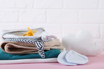 a stack of baby clothes on a light background.