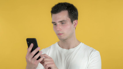 Casual Man Browsing Smartphone Isolated on Yellow Background