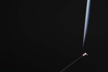 The aromatic stick smokes against a black background close-up. Aromatherapy and Oriental Relaxation