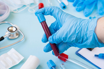 A doctor or nurse holds a test tube to send it to the lab for a blood test. hands of a laboratory assistant with a test tube for taking a blood sample for a virus or flu. Vaccine against the virus 