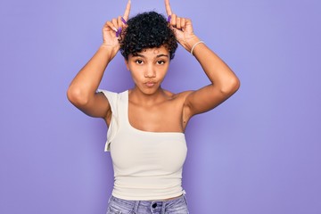 Young beautiful african american afro woman wearing casual t-shirt over purple background doing...