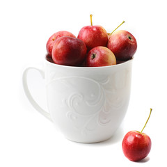 food photograph of red fresh little paradise apples in a large ceramic mug close-up on a white background isolated