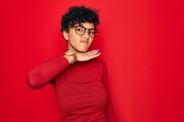 Fototapeta na wymiar Young beautiful african american afro woman wearing turtleneck sweater and glasses cutting throat with hand as knife, threaten aggression with furious violence