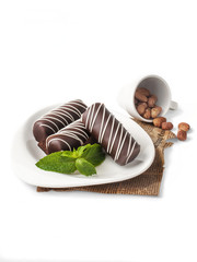 food photography of pastries, chocolate bars (candy, bon bon) with nut filling side view with mint, covered with sugar icing on a white background isolated close up