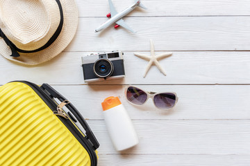 Top View Summer Travel and Plan.  Yellow suitcase luggage with accessories fashion, old camera, sunblock on the colorful background in holiday trips.   Summer and Travel Concept