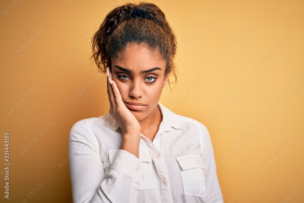 Canvas Prints Young beautiful african american girl wearing casual shirt standing over yellow background thinking looking tired and bored with depression problems with crossed arms.