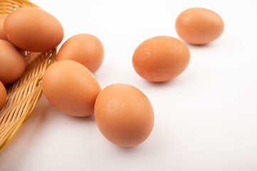 Chicken eggs in a wicker basket and scattered eggs on a white background. Close up.