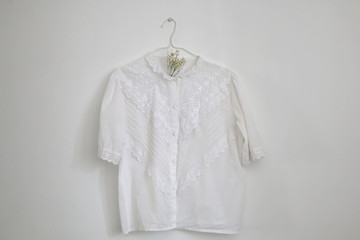 White vintage blouse on a hanger and gypsophila flowers. Selective focus.