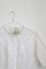 White vintage blouse on a hanger and gypsophila flowers. Selective focus.